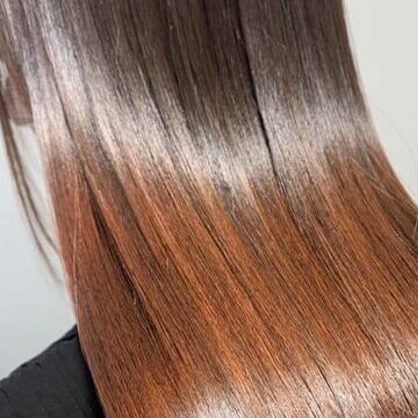 Primo piano di capelli lisci e setosi con sfumatura ombré dal castano al biondo