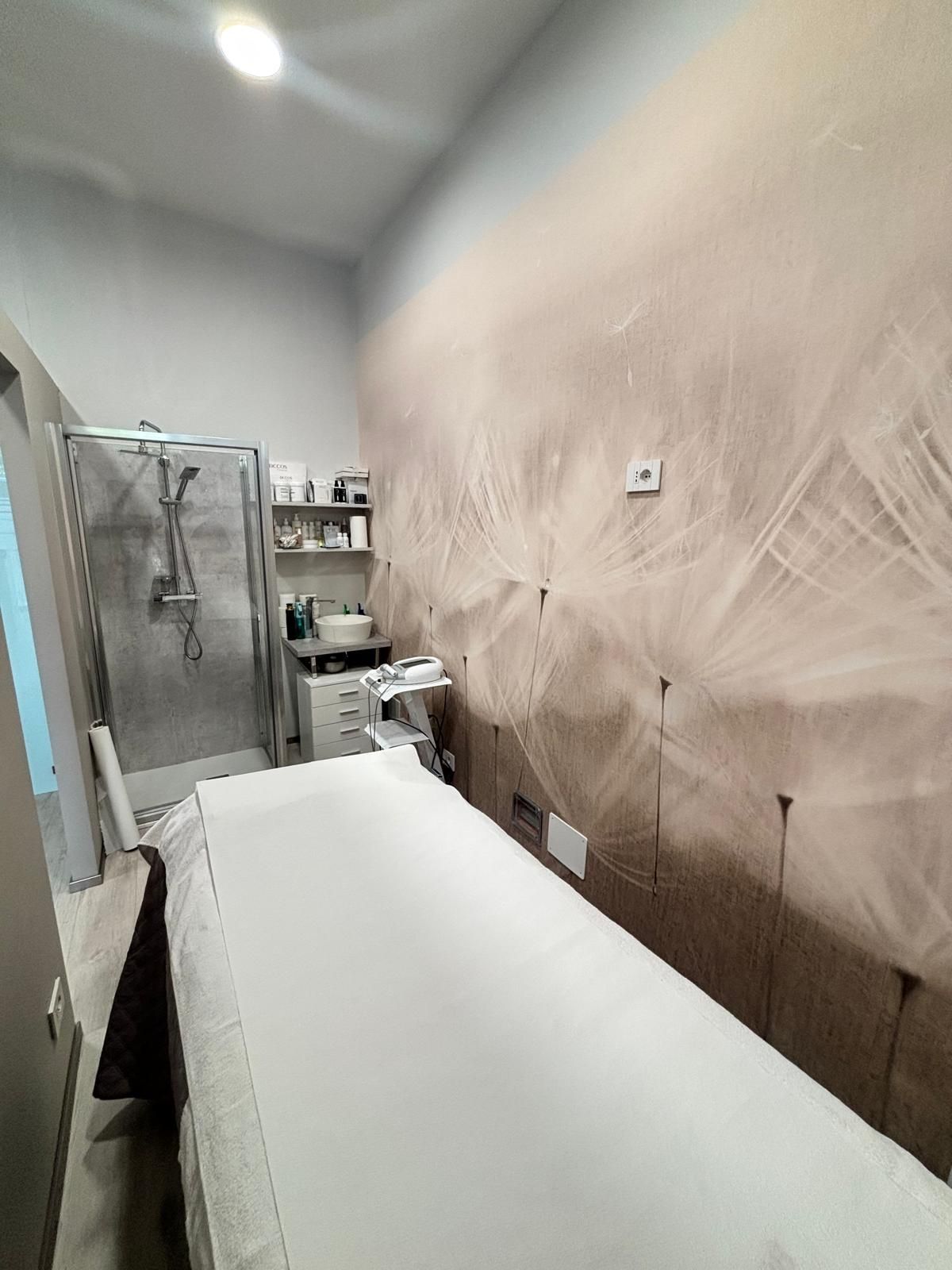 Stanza d’ospedale con un letto, un armadietto, un lavandino e una zona doccia in un piccolo ambiente clinico