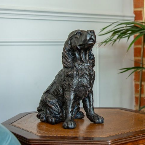 Bronze dog sculpture sitting on a wooden side table.