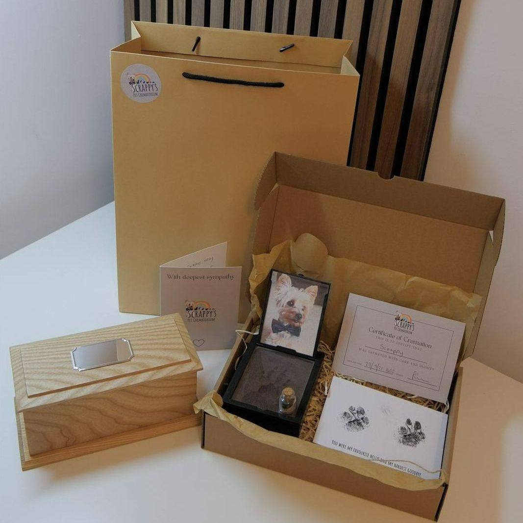 A gift set with a shopping bag, box, wooden box, and cards on a table.