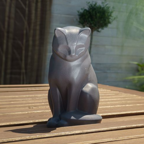 Grey fox statue on a wooden table, outside.