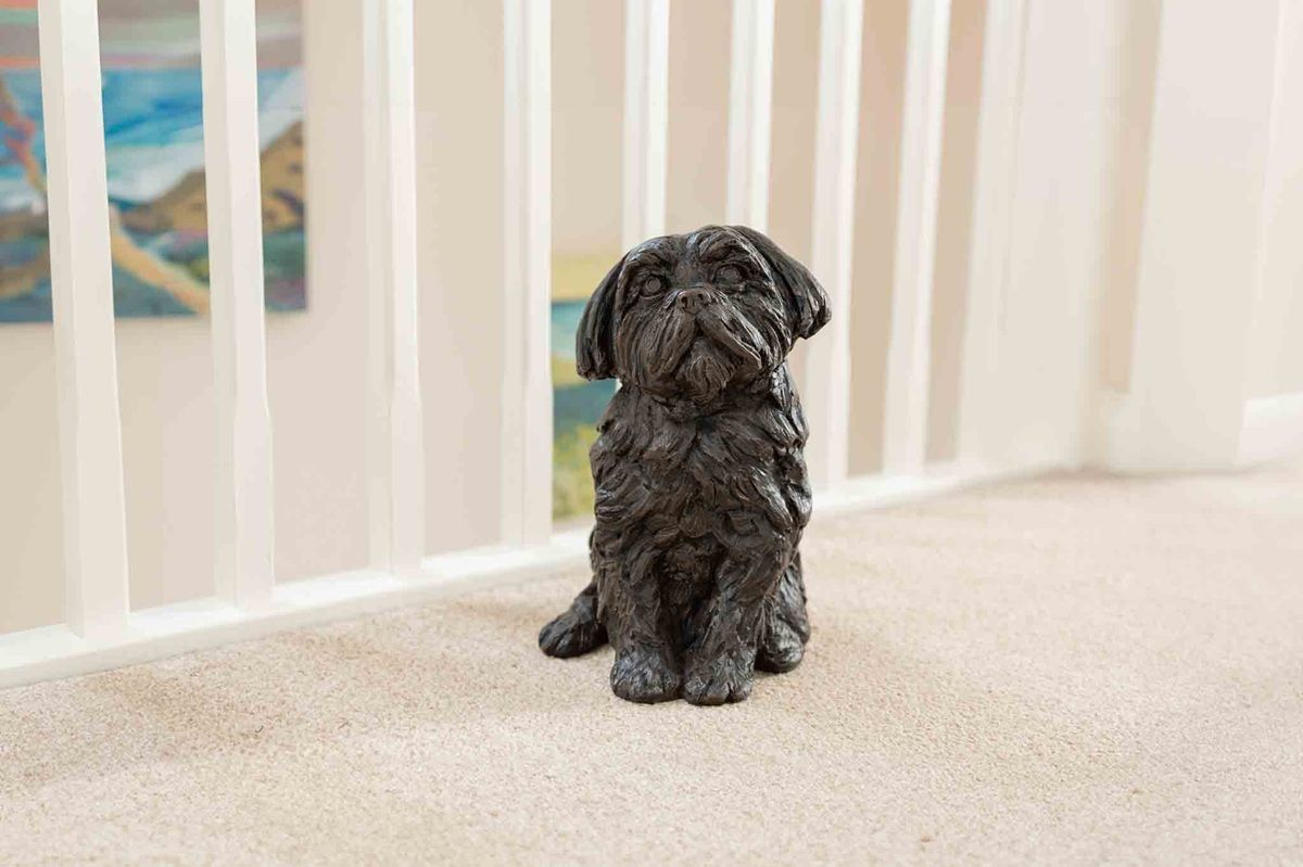 Black dog statue sits on a beige carpet near a white railing.