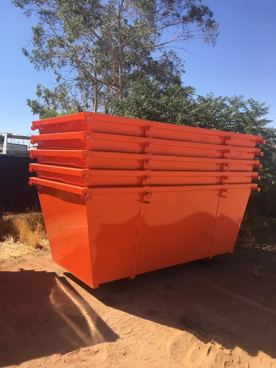 A Stack of Five Bright Orange Metal Dumpsters Sitting on a Dirt — Alice Skip Hire in Alice Springs, NT
