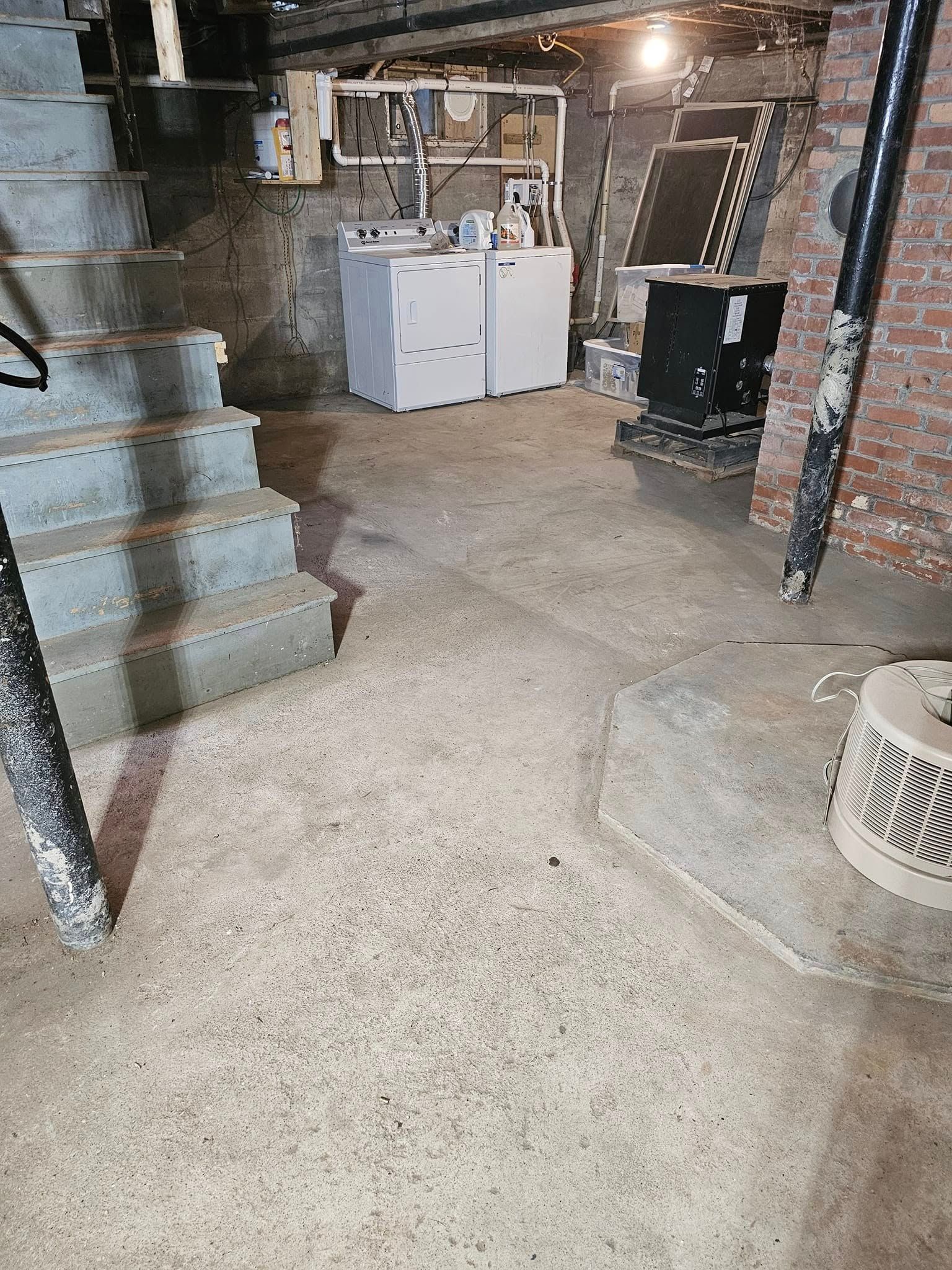 A basement with a washer and dryer and stairs.