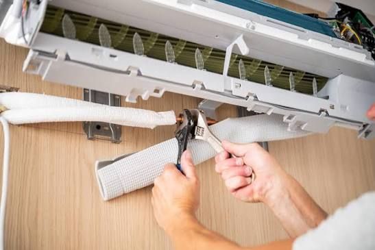 Person installing a cabinet door in a bright kitchen, with tools on the counter and a step ladder nearby