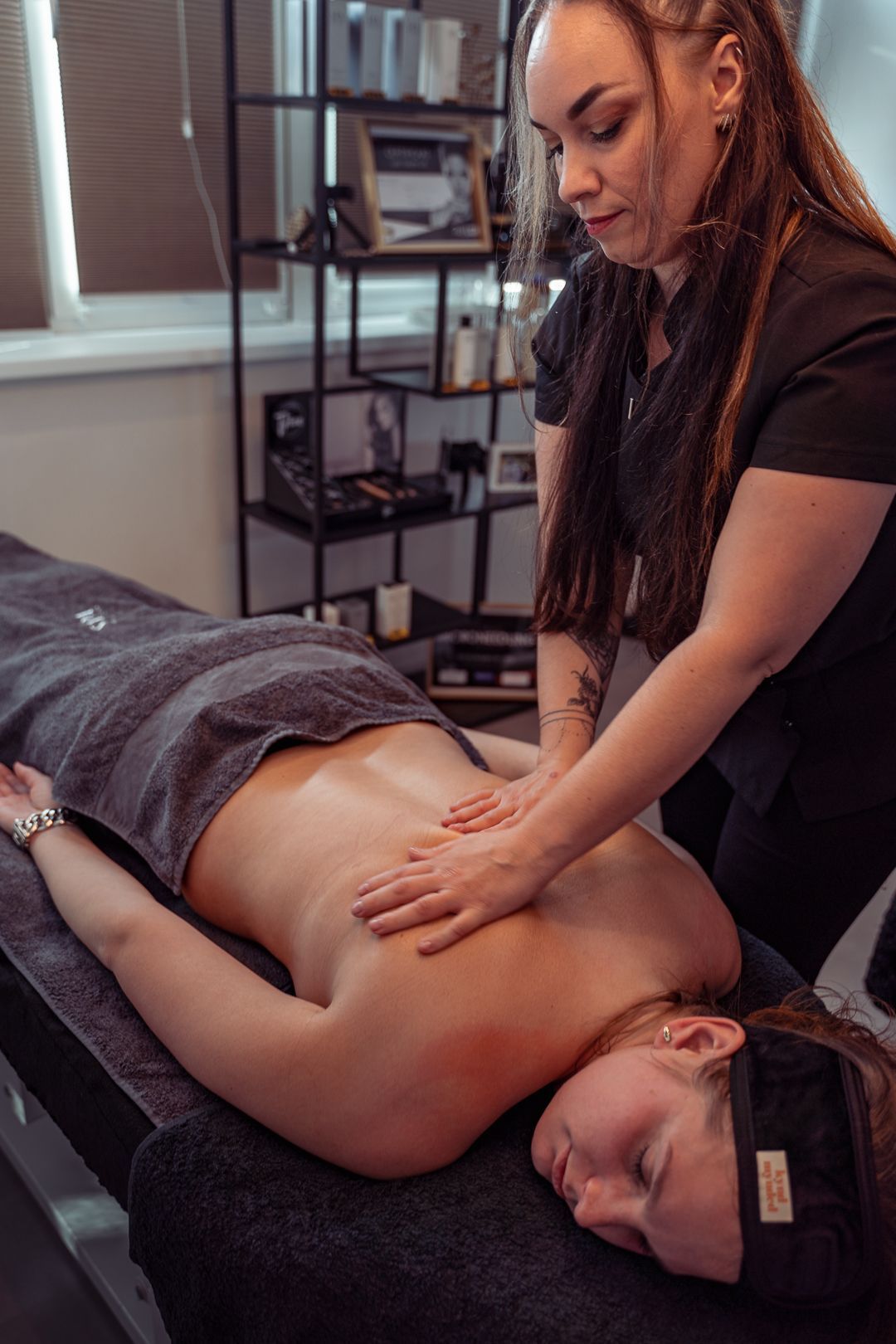 Een massagetherapeut behandelt een cliënt die met het gezicht naar beneden op een massagetafel ligt in een spa.
