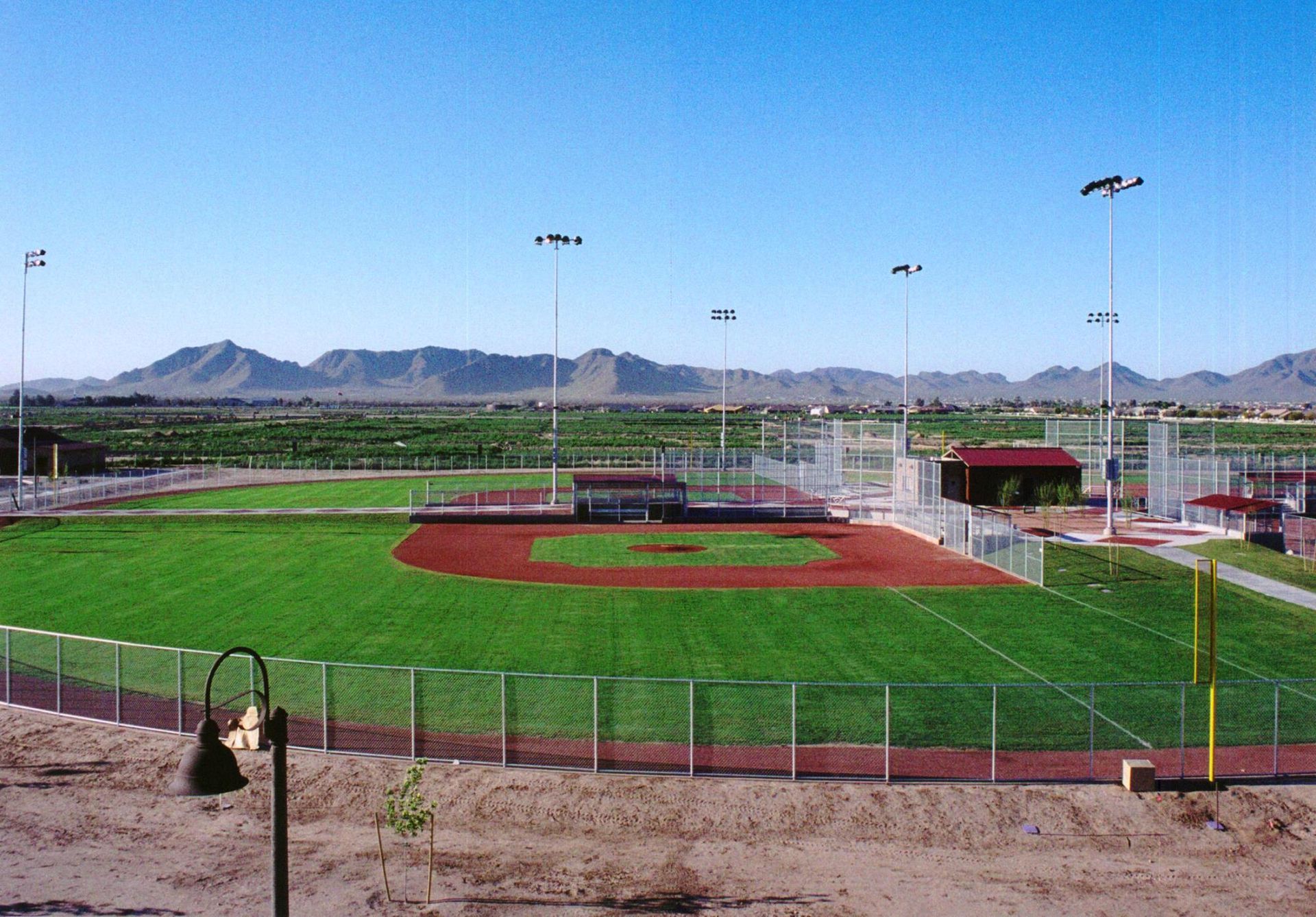 Aerial view of a baseball field with orange infield, green outfield, and surrounding bleachers.