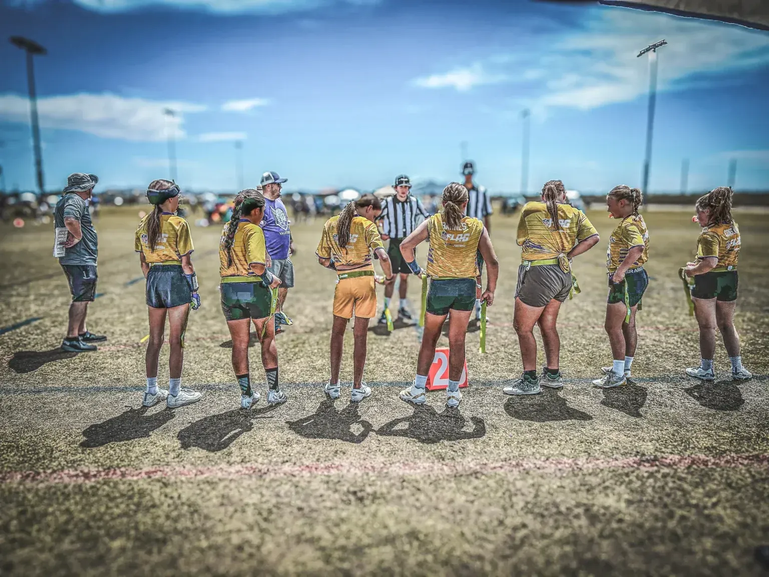 Group of athletes in colorful sportswear standing on a field under a bright blue sky