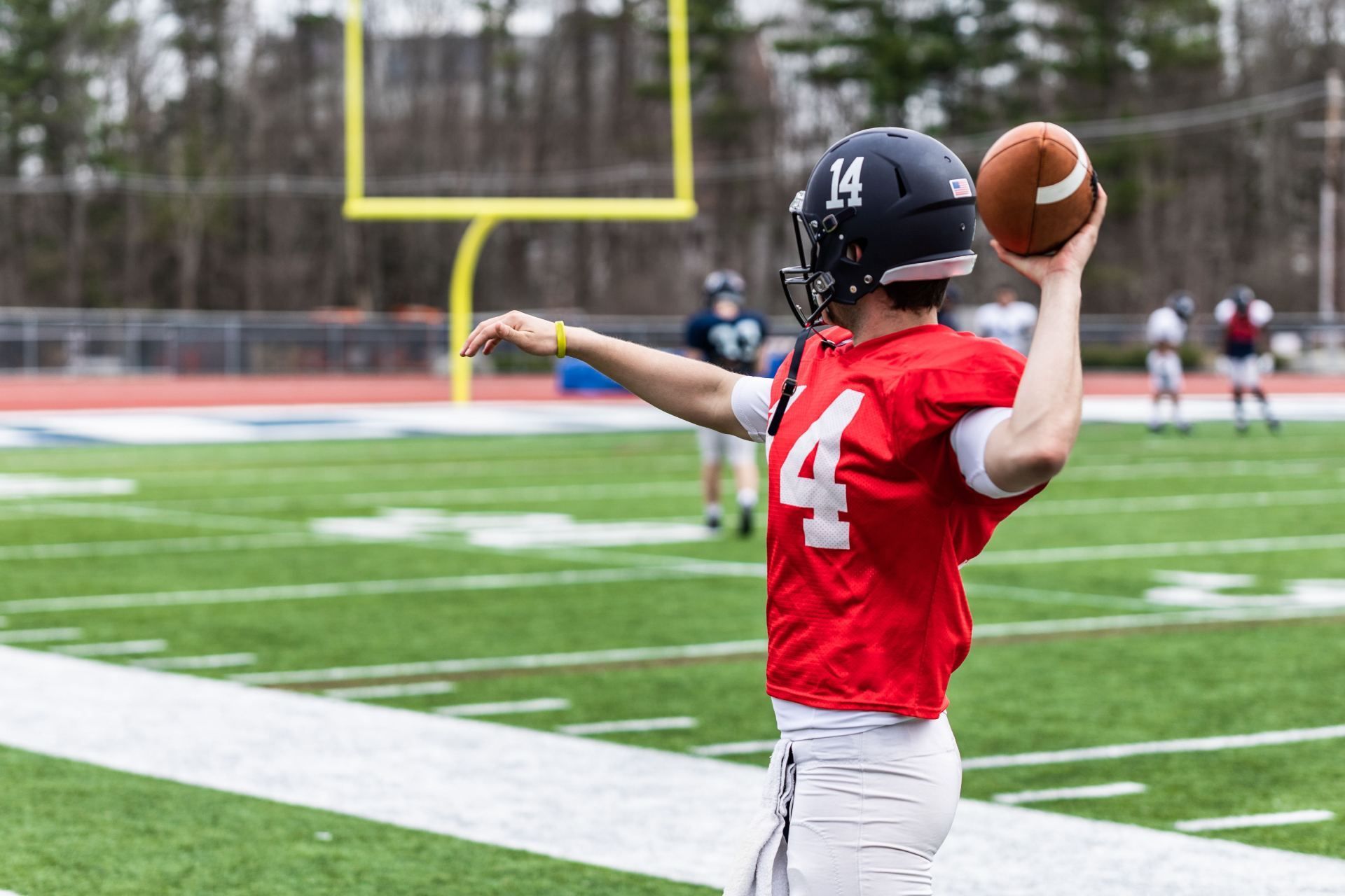 Football player in red jersey throwing a pass on a football field