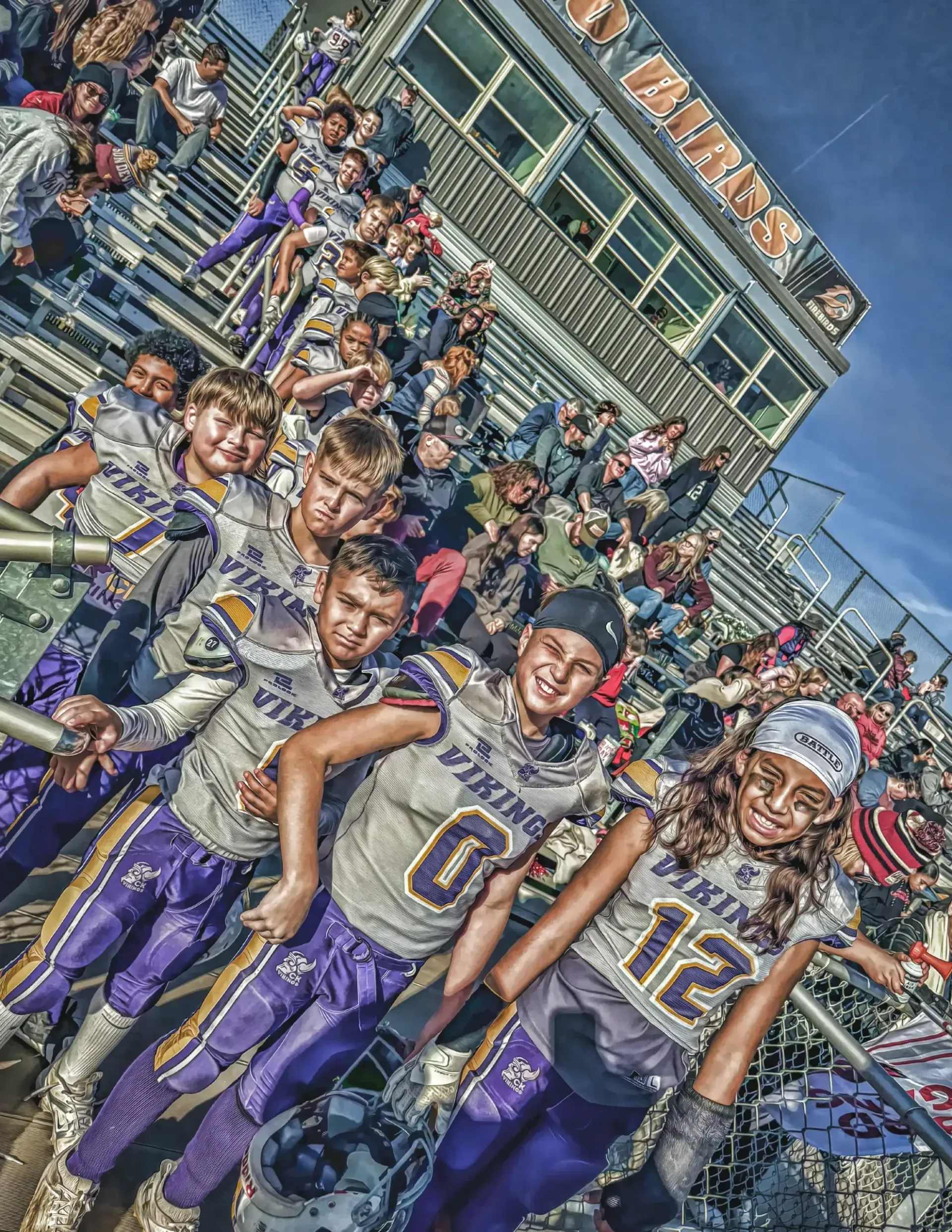 Football players in white and purple uniforms pose on a field in a stadium, celebrating together.