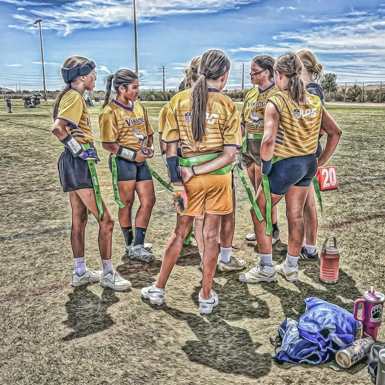 Group of youth field hockey players in yellow jerseys huddle on a sunny outdoor field.