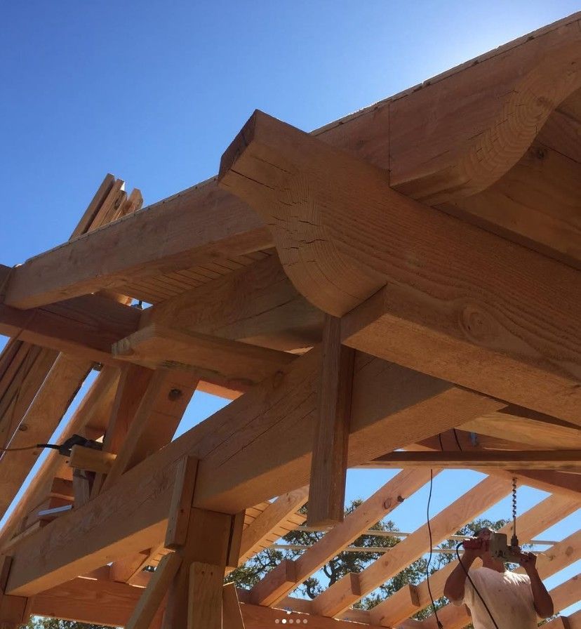 Close-up of wooden roof trusses under construction against a blue sky