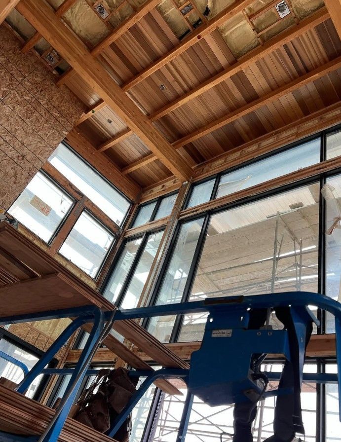 Interior of a modern building with wood ceiling, large windows, and a blue lift platform below