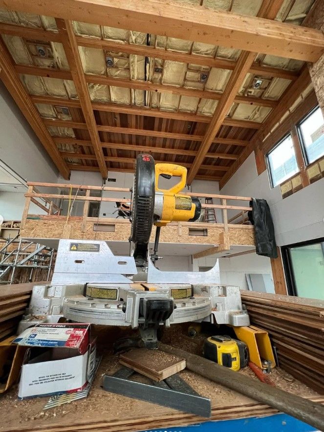 Large saw on a cluttered floor in a wooden workshop with a loft and exposed beams