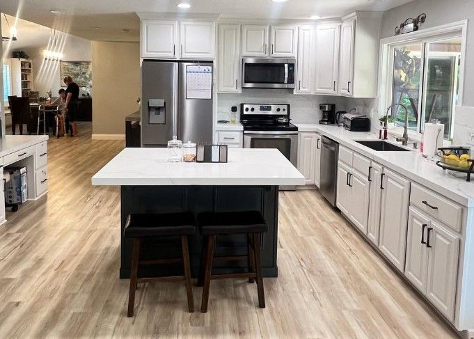 Bright kitchen with white cabinets, stainless appliances, island, and light wood floors