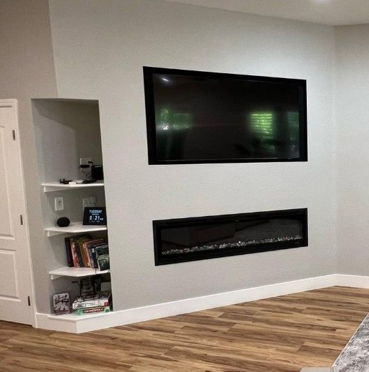 Modern living room wall with a mounted TV, electric fireplace, and built-in shelving nook.
