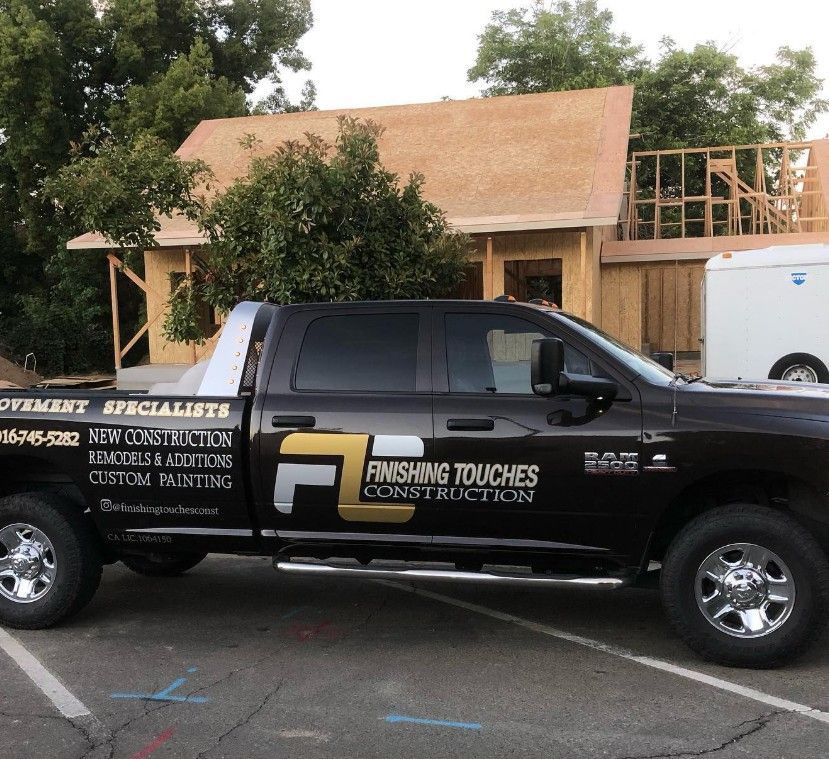 Black construction pickup truck parked in front of a house under renovation with exposed framing