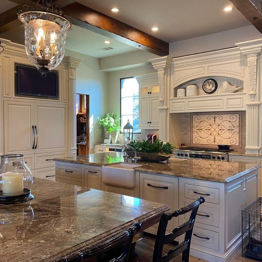 Bright luxury kitchen with white cabinetry, granite island, and decorative range hood