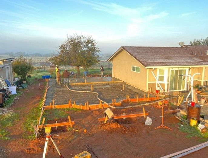 Backyard garden with raised beds, young plants, and a beige house at sunset