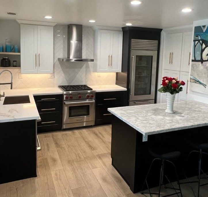 Modern kitchen with black and white cabinets, stainless steel stove, island, and vase of red flowers