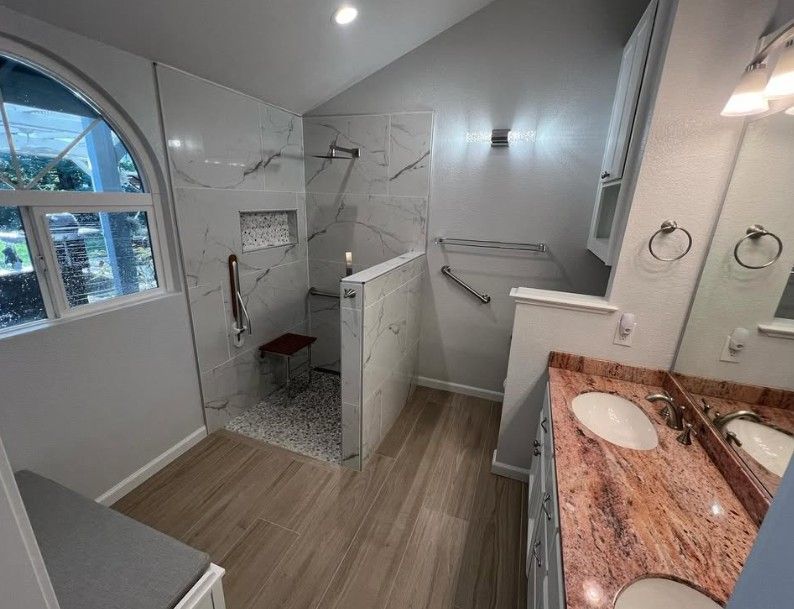 Bright modern bathroom with walk-in shower, double vanity, and gray tile flooring