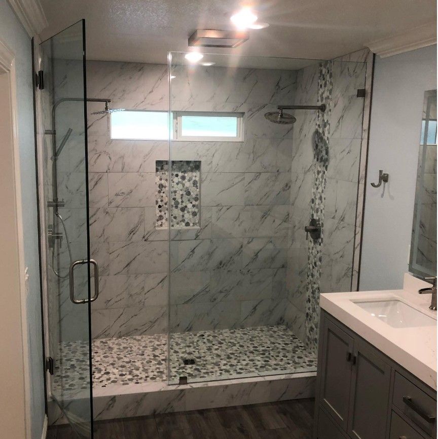 Modern bathroom with marble-look walk-in shower, glass doors, mosaic floor, and vanity sink