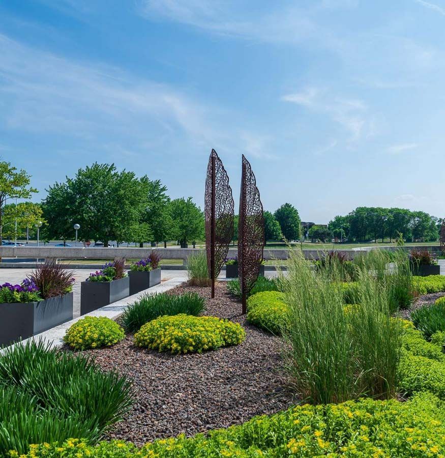 Landscaped garden with decorative metal art under a blue sky.