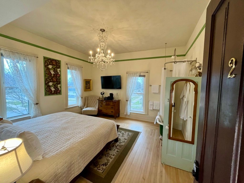 A bedroom with a king size bed , dresser , chair and television.
