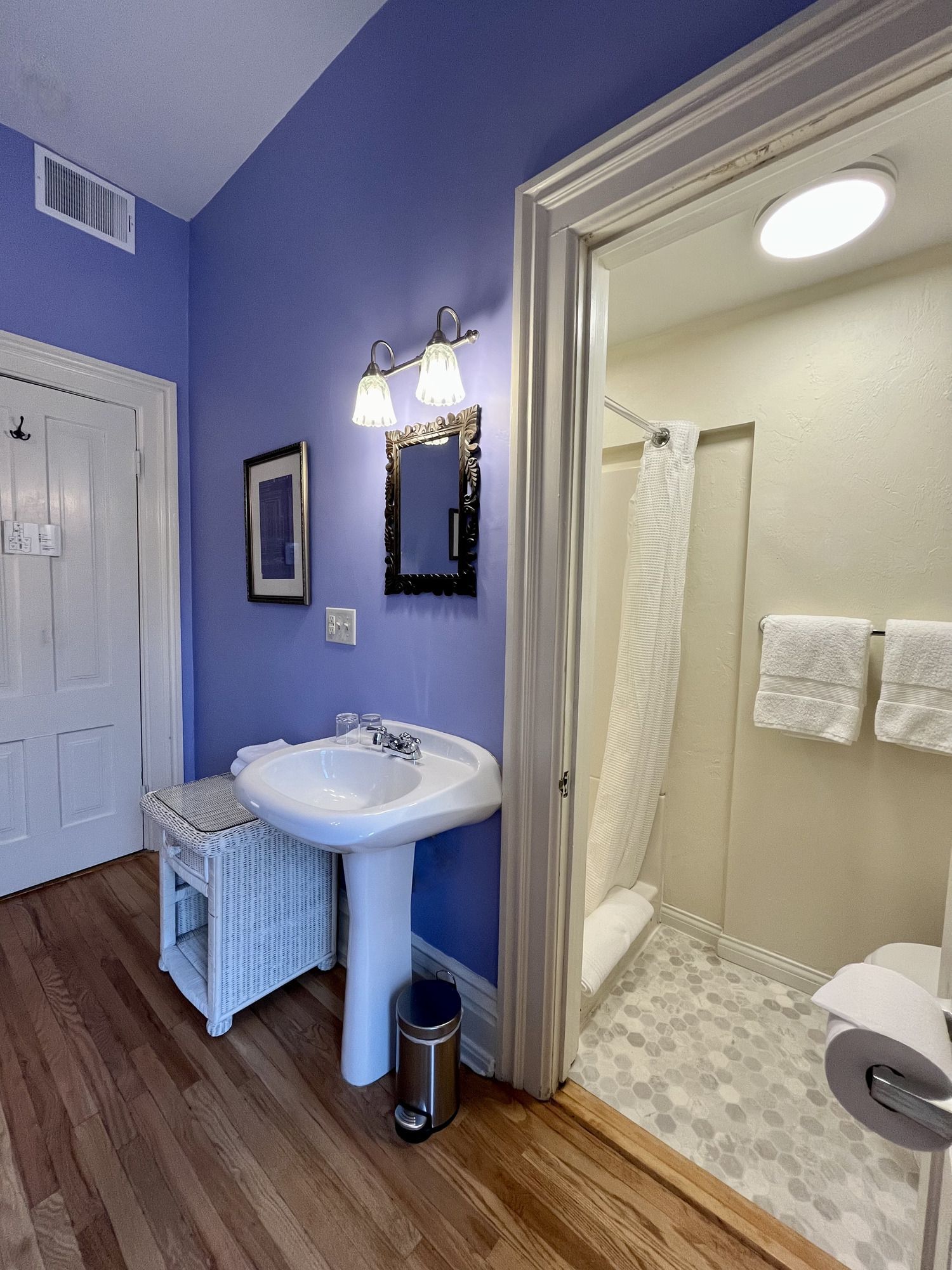 A bathroom with purple walls and a pedestal sink