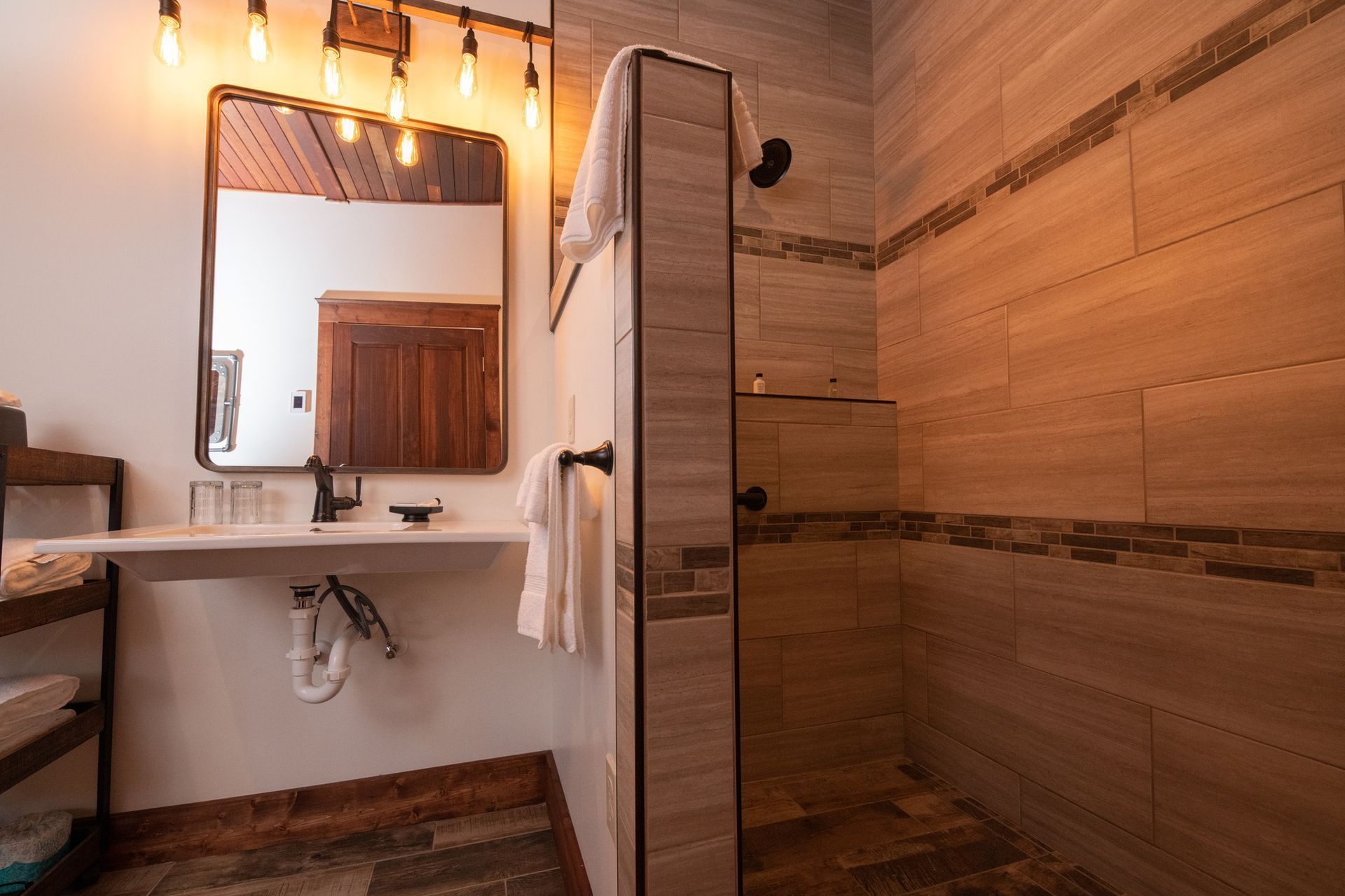 A bathroom with a sink , mirror , and walk in shower.