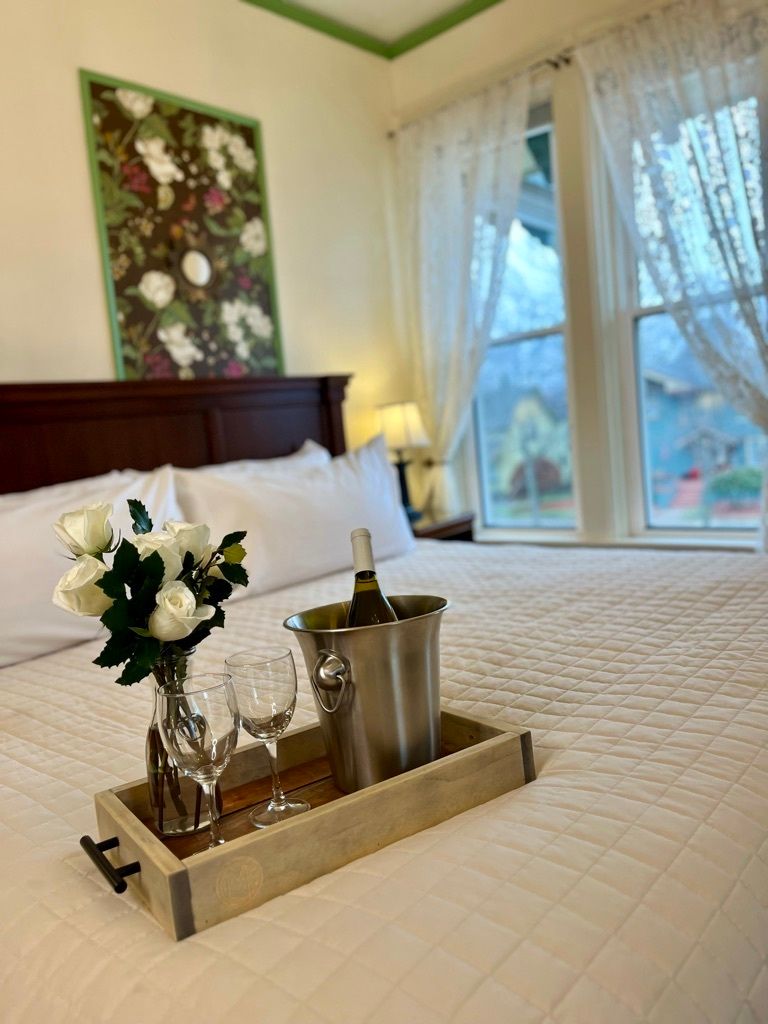 A bed with a tray of wine and glasses on it.