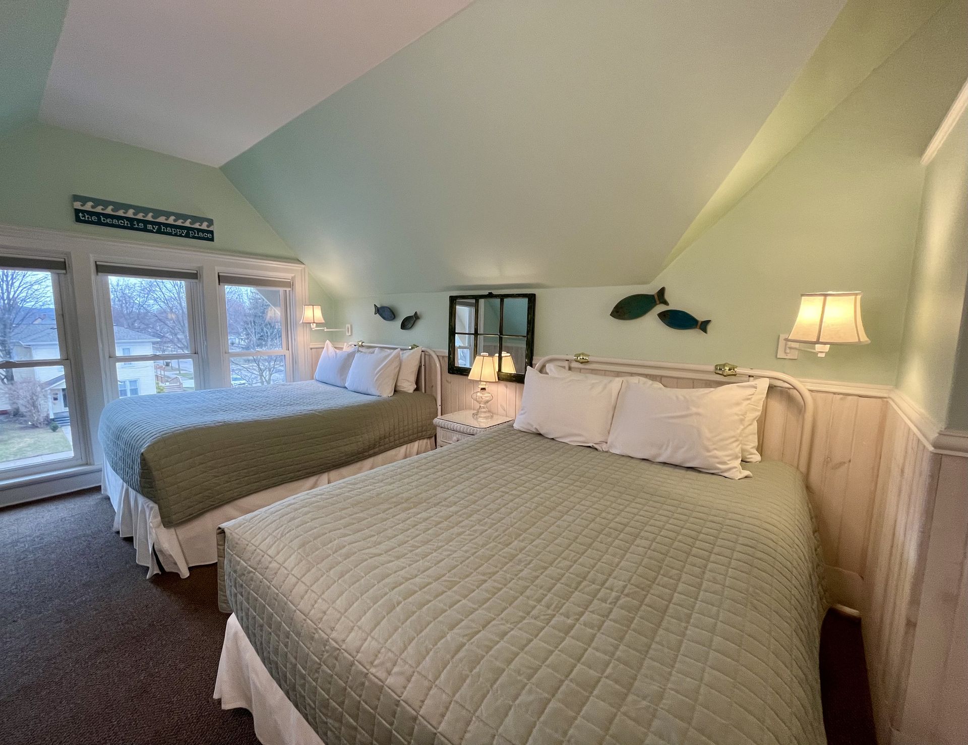 A bedroom with two beds and a large window.