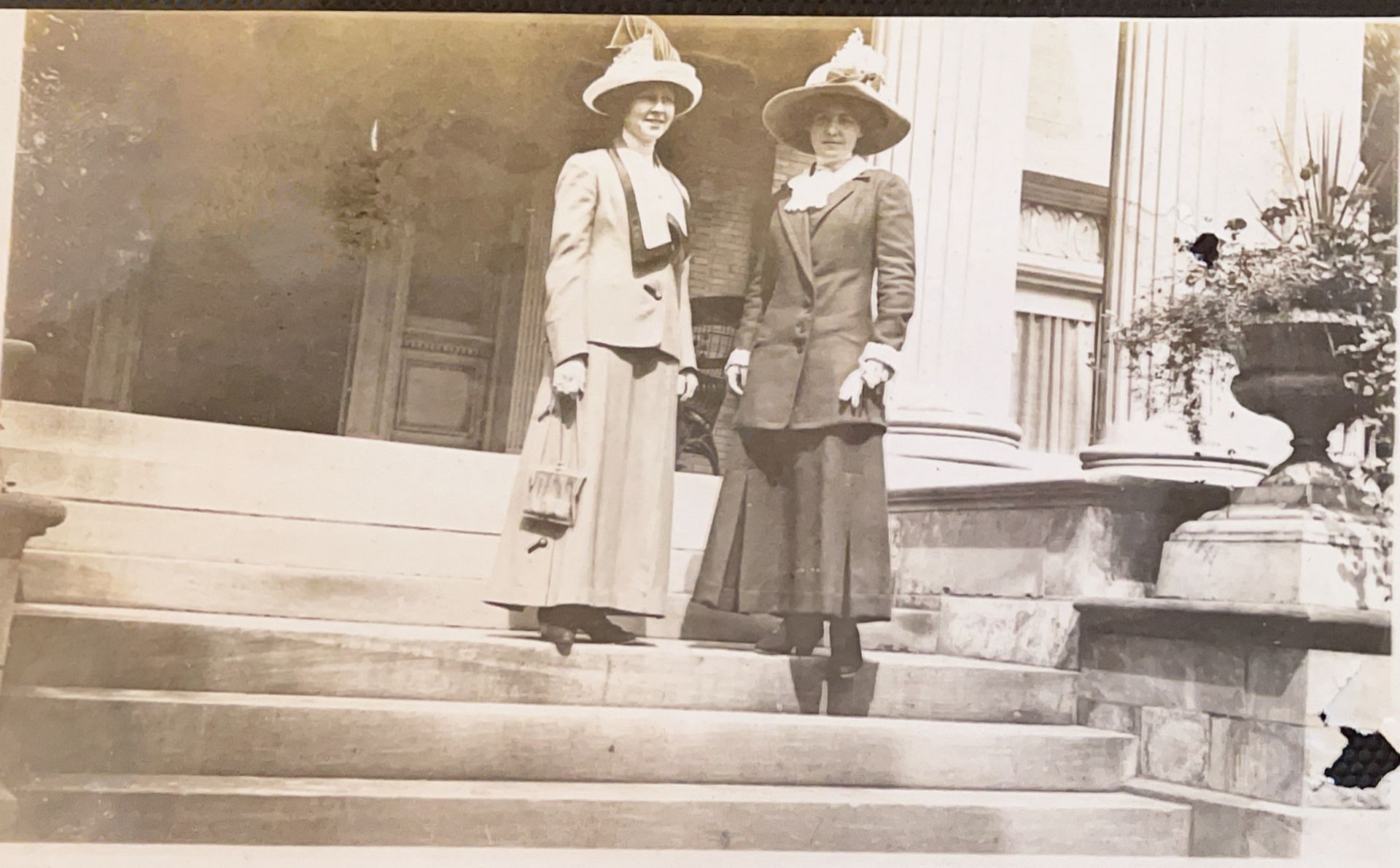 Two women are standing on the steps of a building