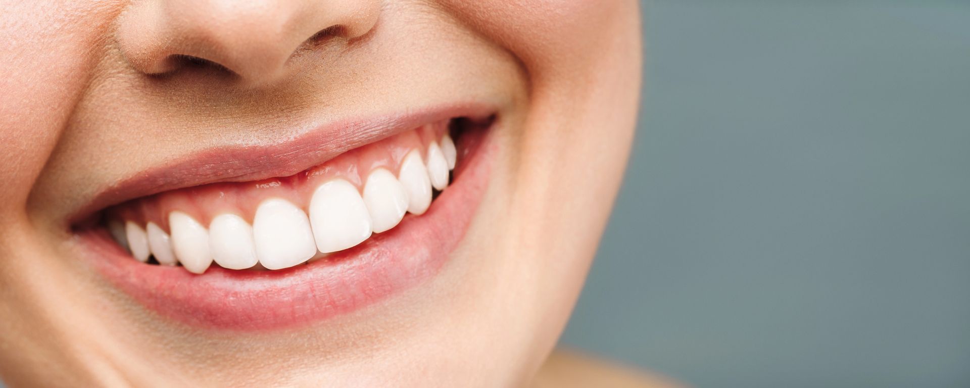 Primo piano di una persona con un sorriso smagliante e ampio che mostra denti sani e bianchi.