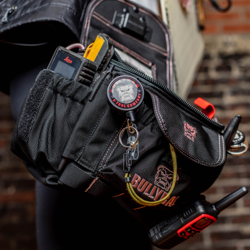A black tool belt with multiple pockets, holding a radio, laser level, and keys.