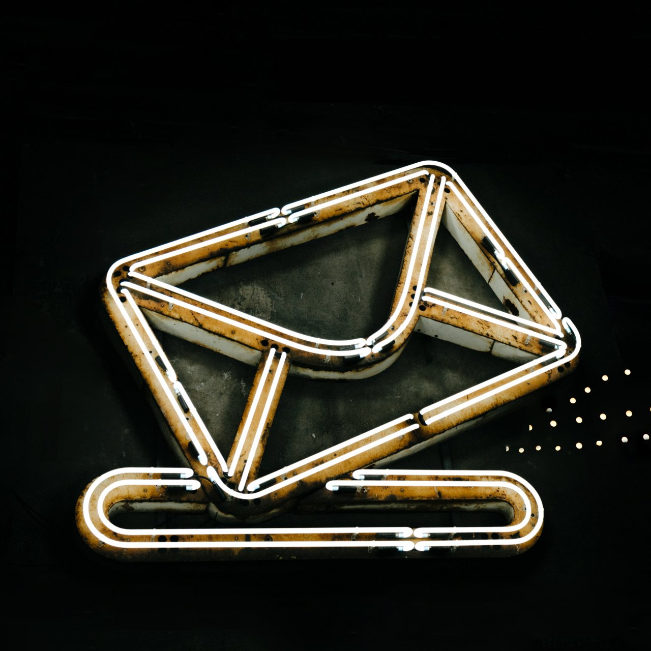 A neon sign of an envelope on a black background