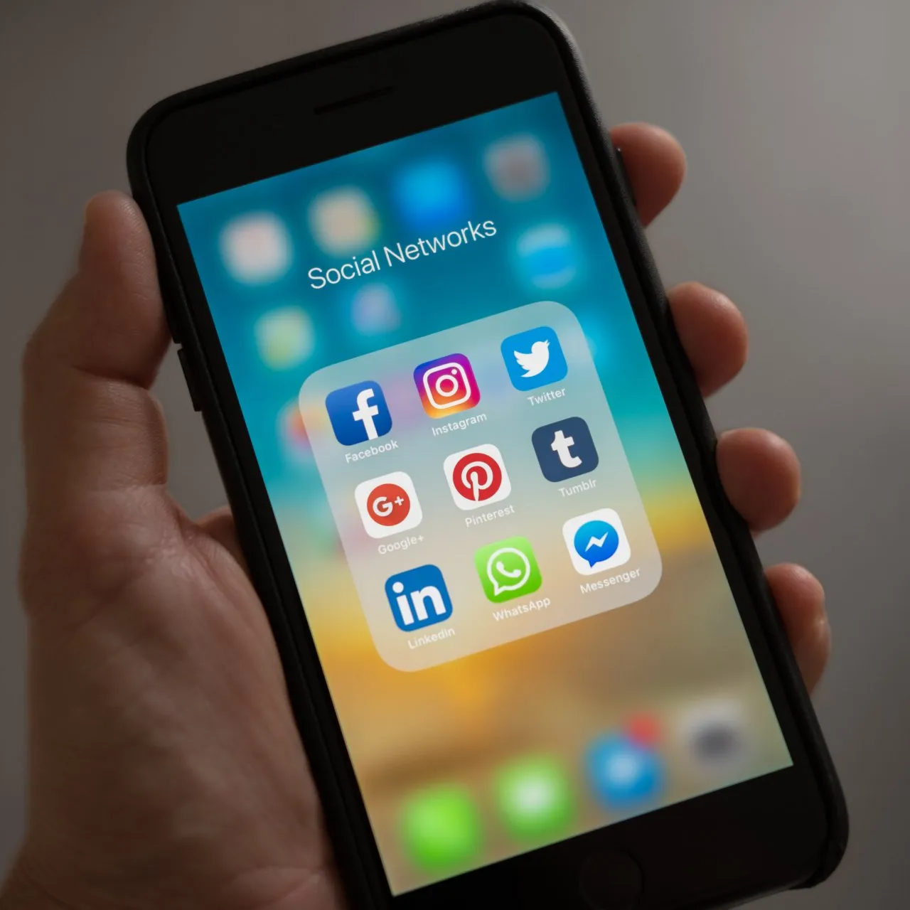 A person is holding a cell phone with social networks on the screen