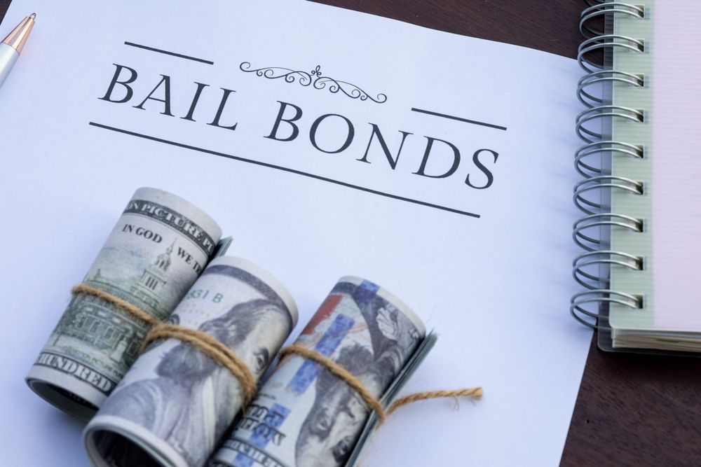 “BAIL BONDS” sign with rolled cash tied by string on a notebook page