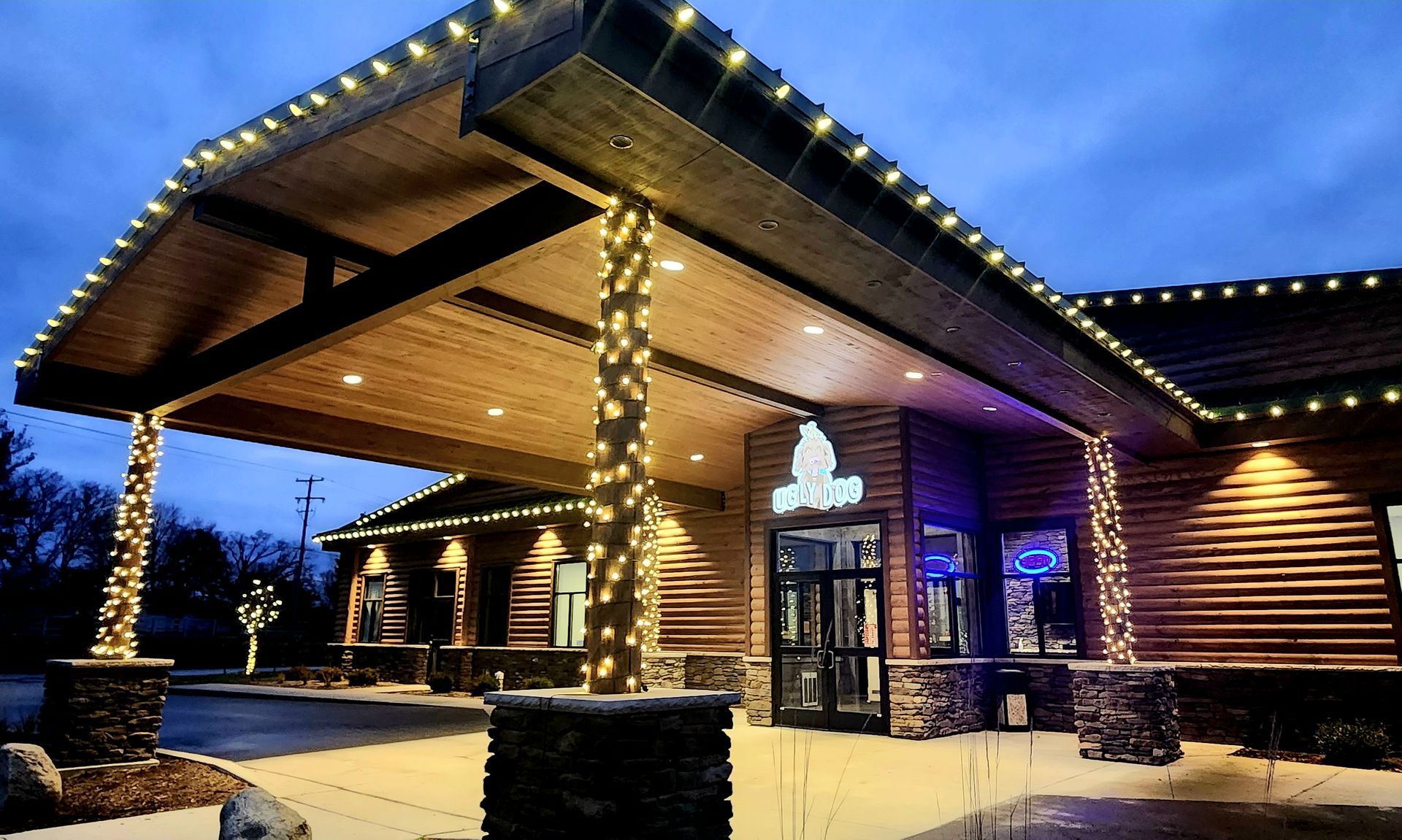 Log cabin-style building at dusk with warm string lights and snow on the ground
