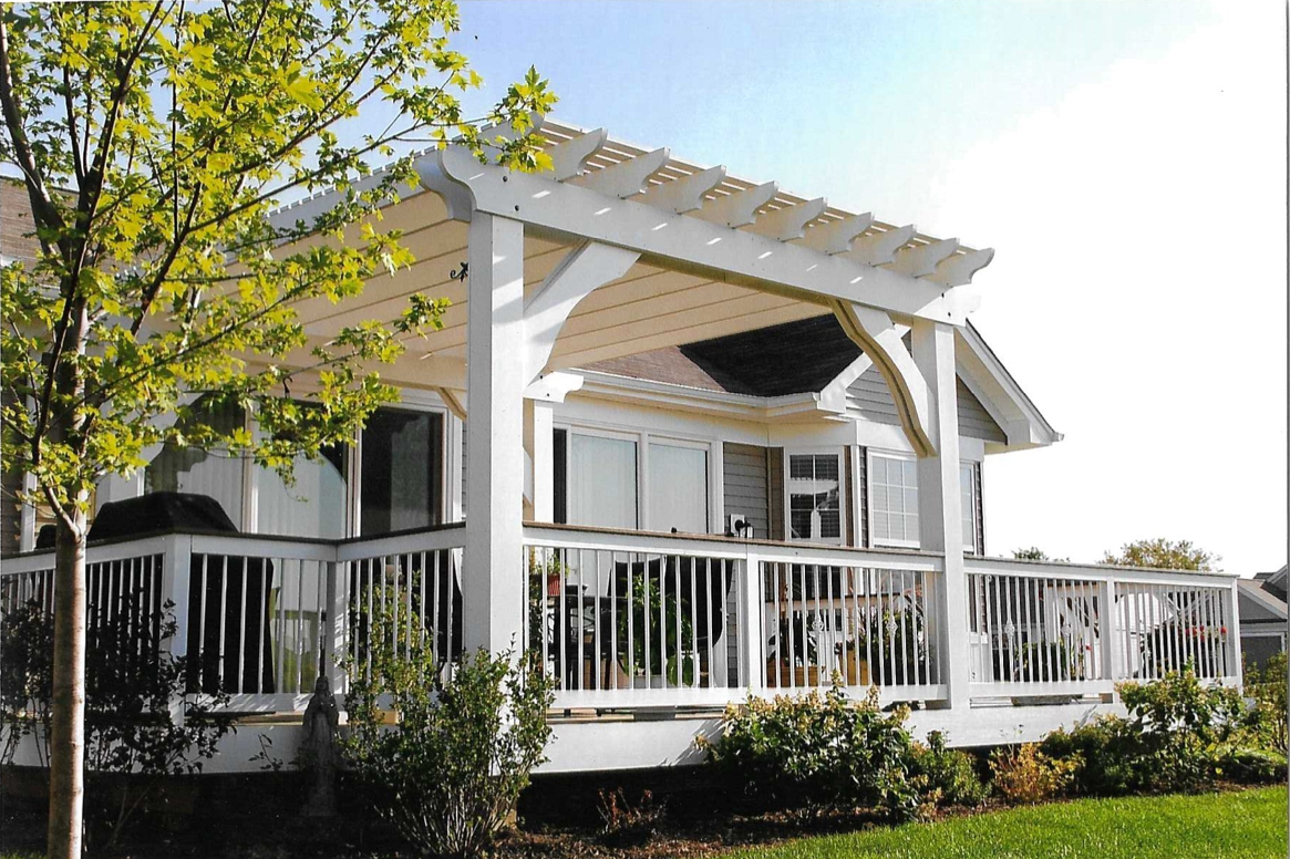 A white house with a large deck and a pergola