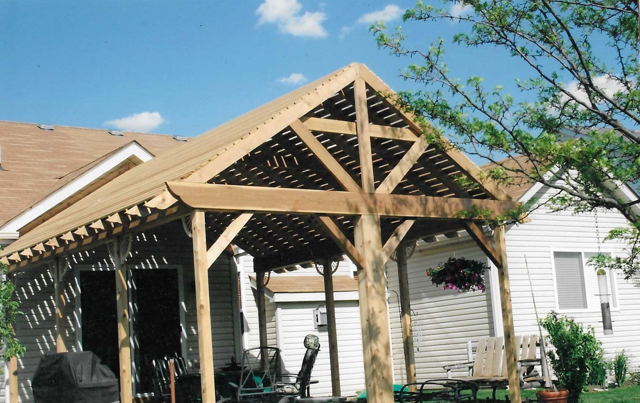 A wooden pergola is sitting in front of a house