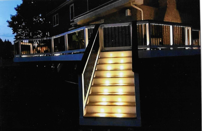 A deck with stairs that are lit up at night