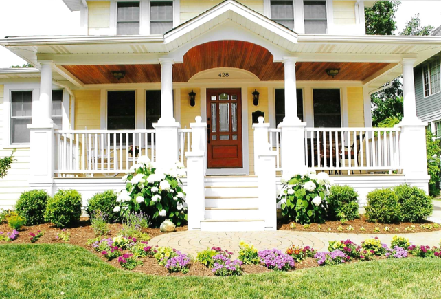 A house with a porch and flowers in front of it