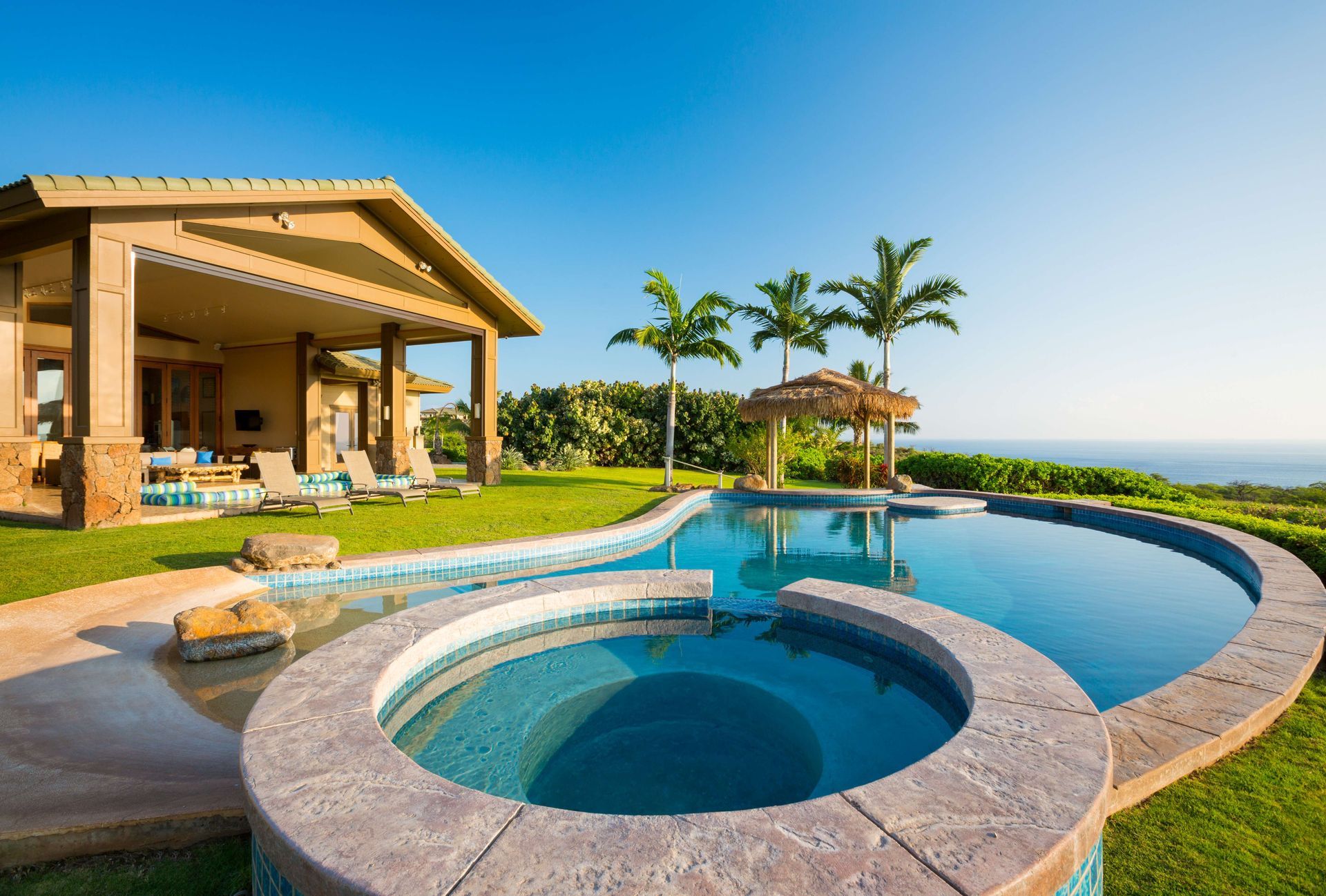 Luxury resort pool with hot tub, palm trees, and ocean view beside a villa Luxury resort pool with hot tub, palm trees, and ocean view beside a villa