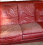 Red leather couch with worn seat cushions.