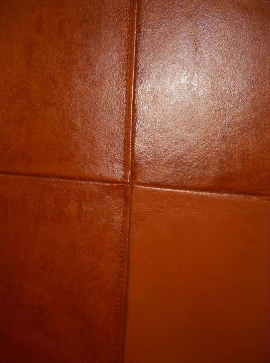 Close-up of brown leather upholstery with stitched seams.