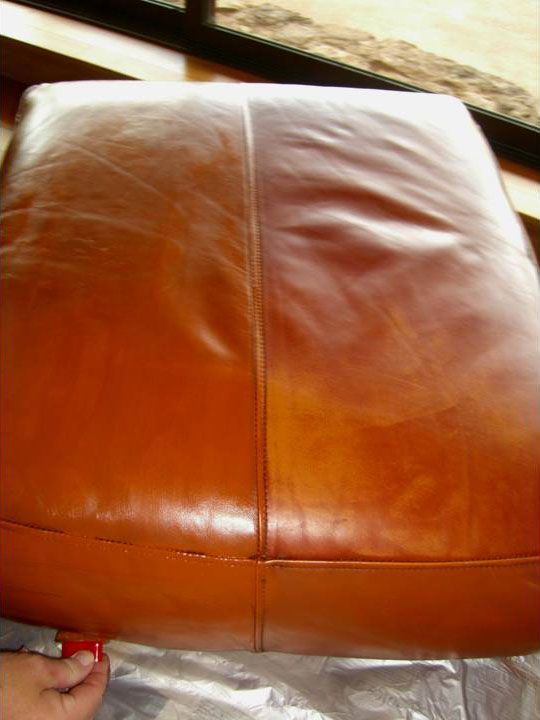 Leather chair seat, half restored. The right side is a richer, darker brown than the left, which has scratches.