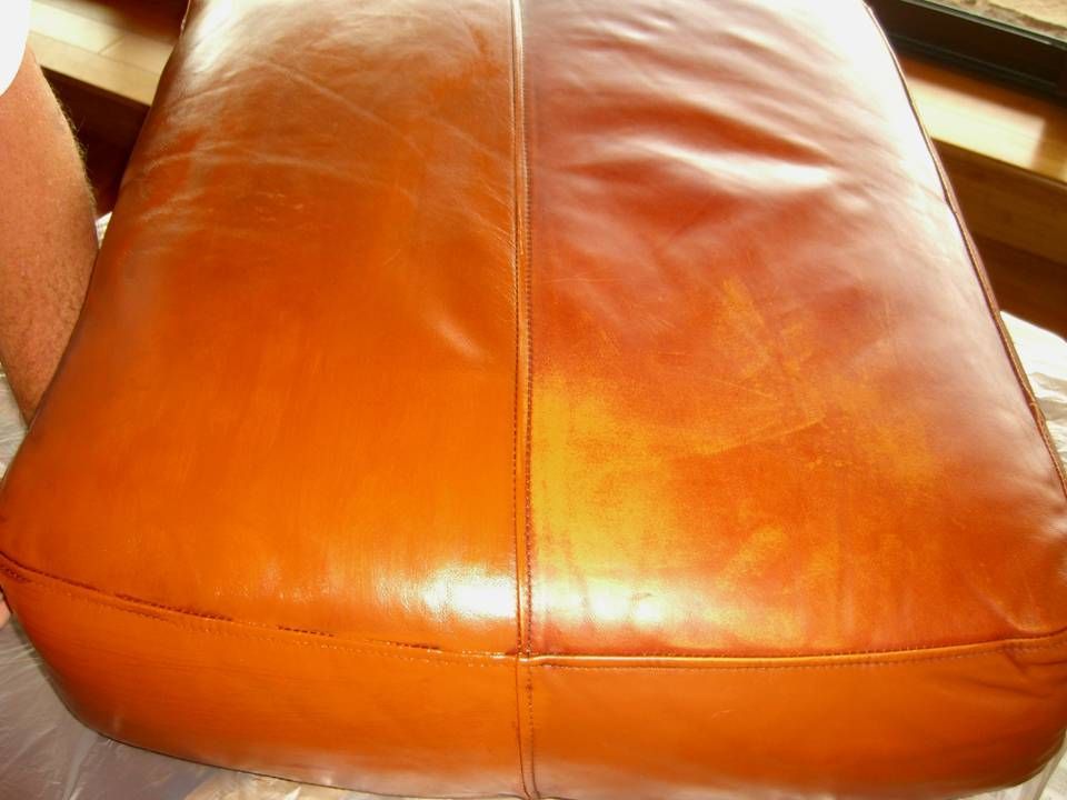 A leather cushion split into two sections, one cleaned and shiny, the other dull with scratches; brown.