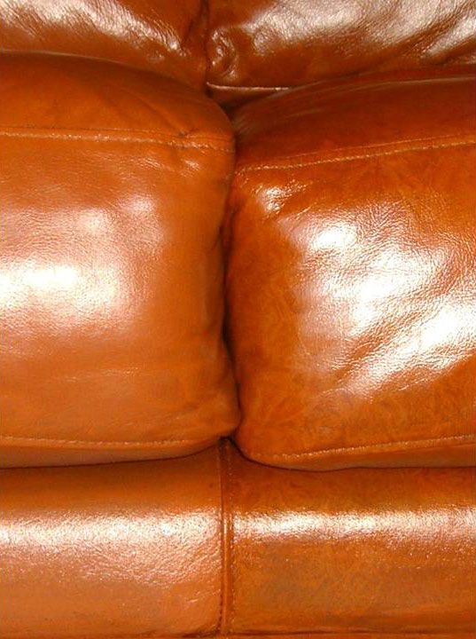 Close-up of a brown leather couch with glossy cushions.