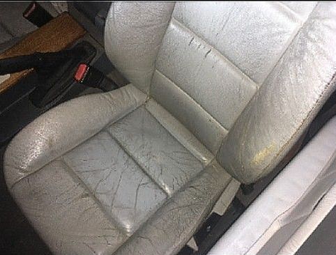 Gray, cracked leather car seat, with visible wear and tear.